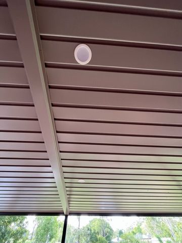 Overhead view of a brown and white striped patio roof with a white circular speaker — Steel Homes Australia in Branyan, QLD