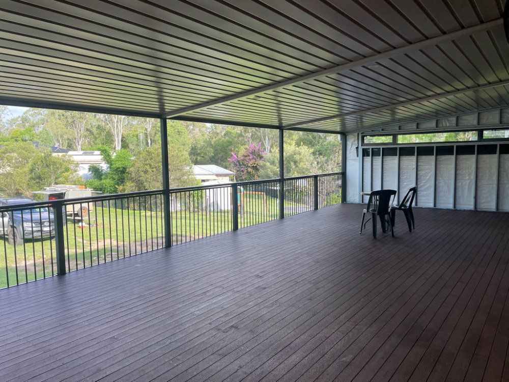 Covered wooden deck overlooking a yard with trees and houses. Two chairs are on the deck — Steel Homes Australia in Branyan, QLD