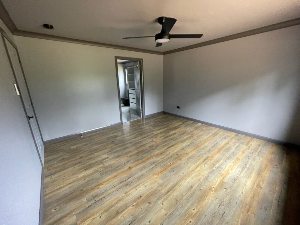 Empty room with wood-look flooring, gray walls, a ceiling fan, and a doorway leading to another room — Steel Homes Australia in Branyan, QLD