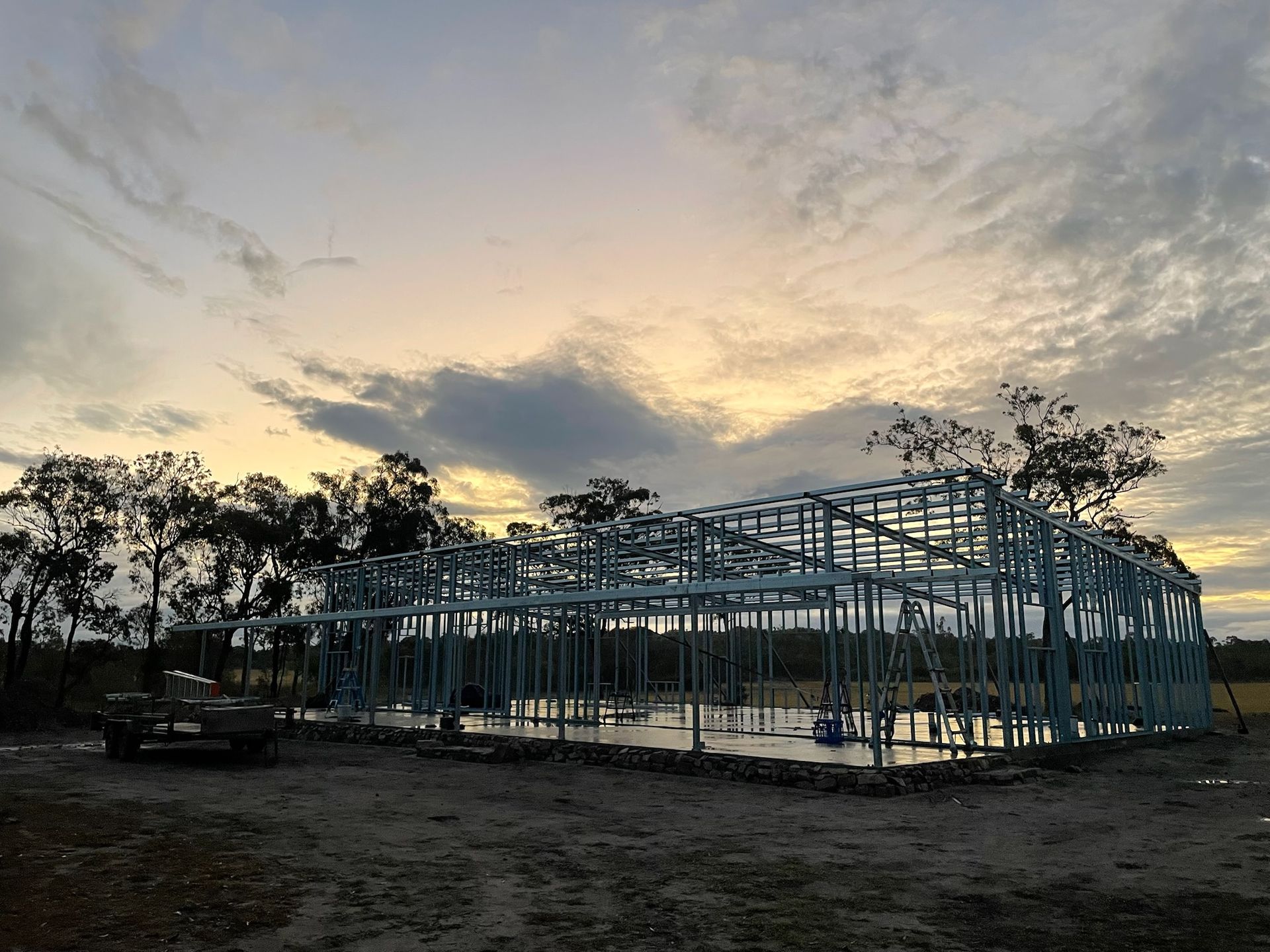 Construction site with steel frame of a building against a dusky sky — Steel Homes Australia in Branyan, QLD