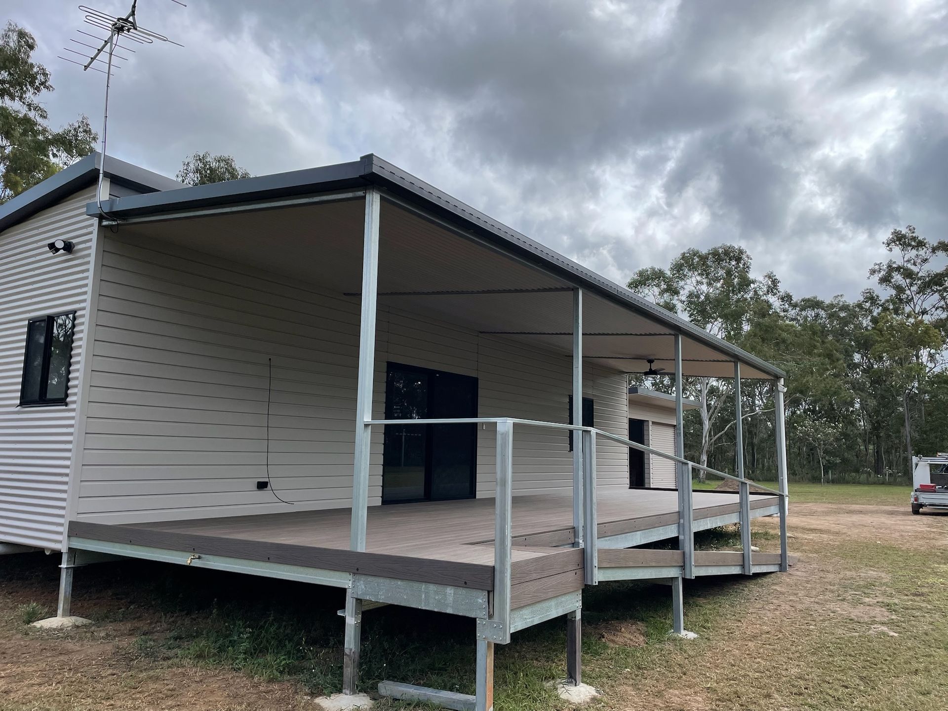 House with deck and awning, gray siding, metal frame, on a grassy lot under a cloudy sky — Steel Homes Australia in Branyan, QLD