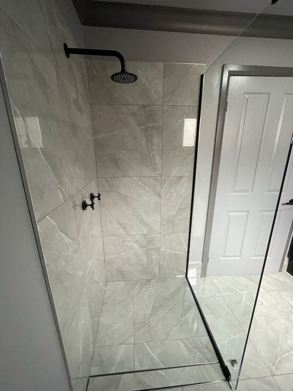 Shower stall with black fixtures, grey tile, and glass door — Steel Homes Australia in Branyan, QLD
