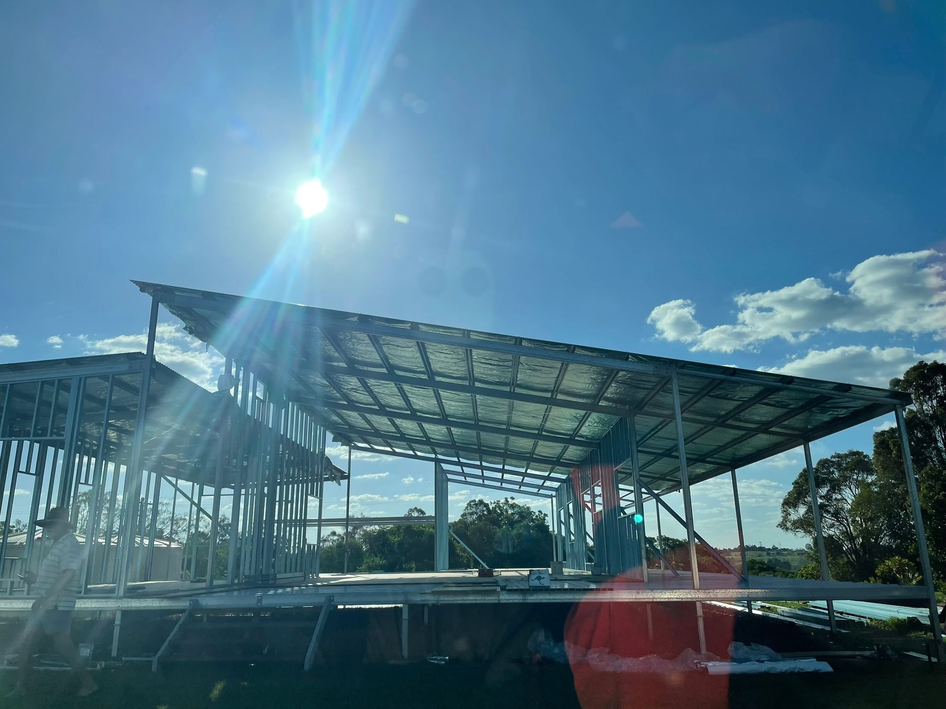 Construction of a metal-framed building under a bright sun and blue sky — Steel Homes Australia in Branyan, QLD