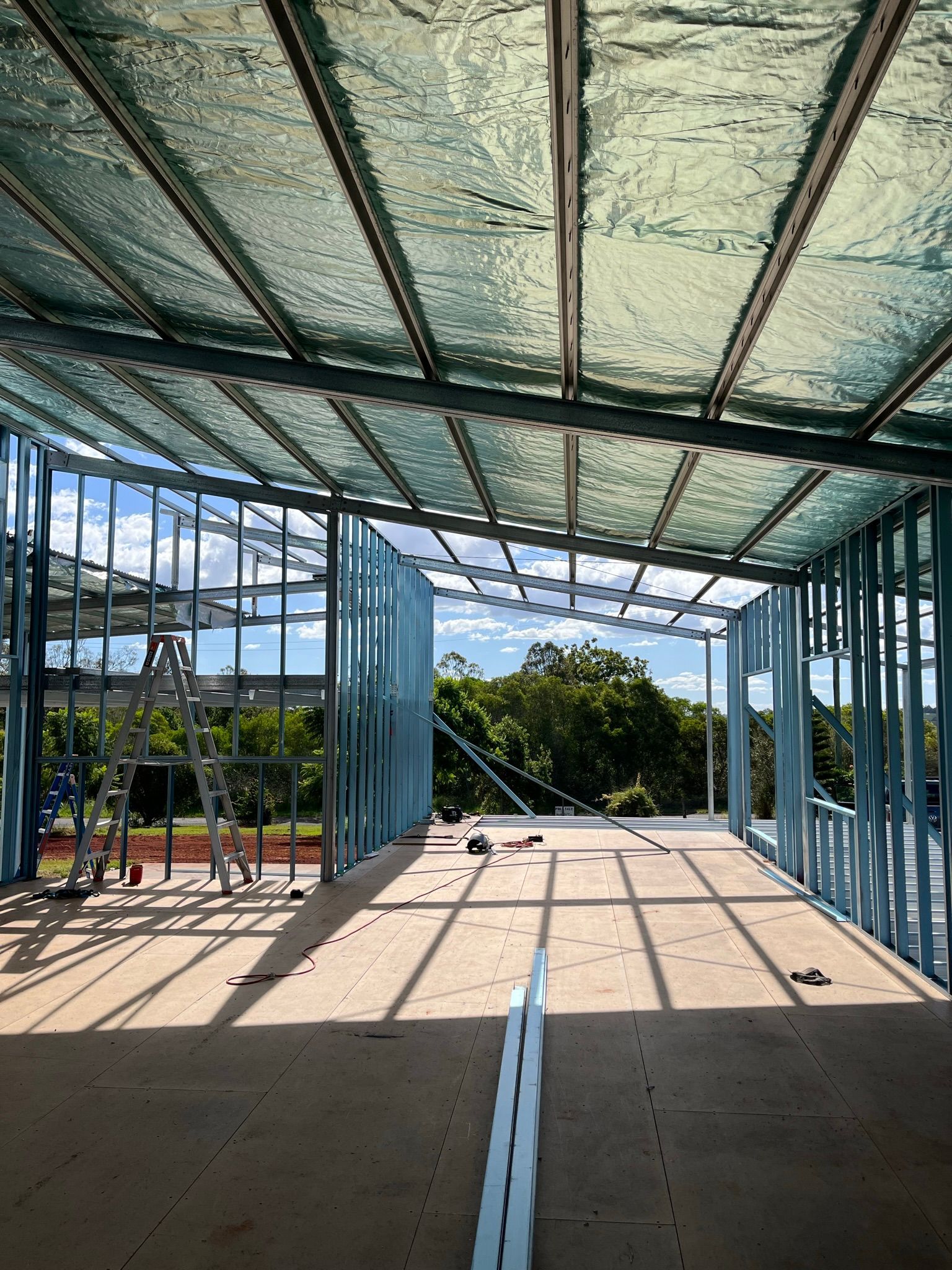 Interior of a building under construction with metal framing and insulation, view of a wooded landscape outside — Steel Homes Australia in Gin Gin, QLD