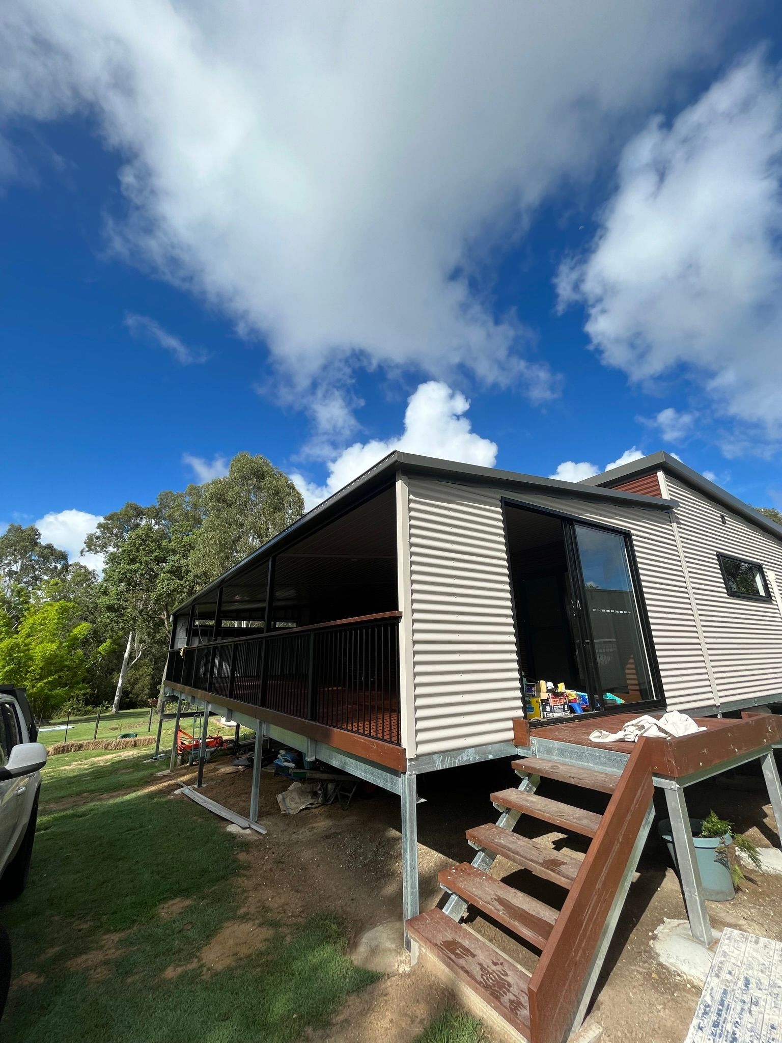 A house with a porch, stairs, and a blue sky with clouds — Steel Homes Australia in Branyan, QLD