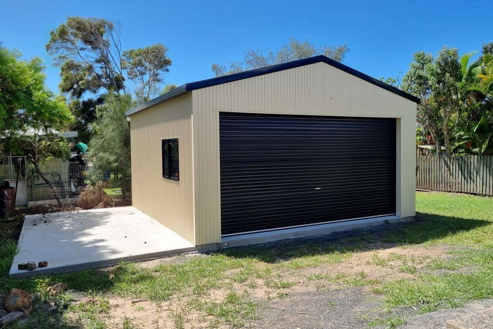 A Garage With a Black Door is Sitting in the Middle of a Grassy Field — Steel Homes Australia in Branyan, QLD