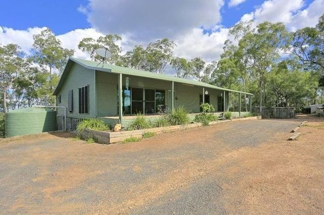 A Green House With a Porch and Trees in the Background — Steel Homes Australia in Branyan, QLD