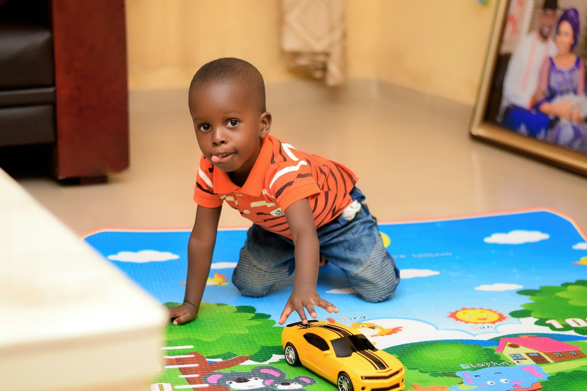 A young boy is playing with a toy car on a rug.