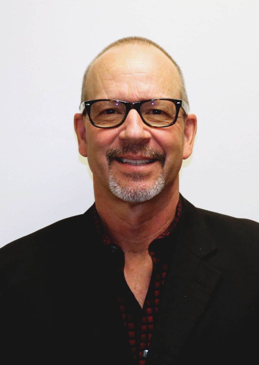 A man with glasses and a beard is smiling for the camera