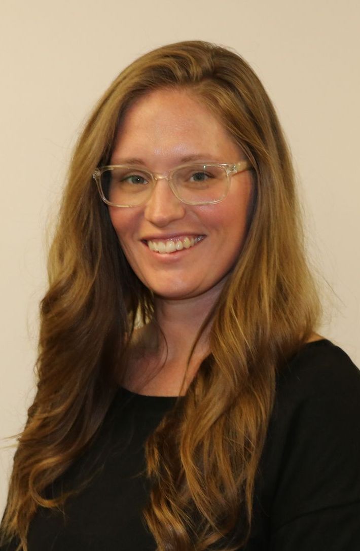 A woman wearing glasses and a black shirt is smiling for the camera.