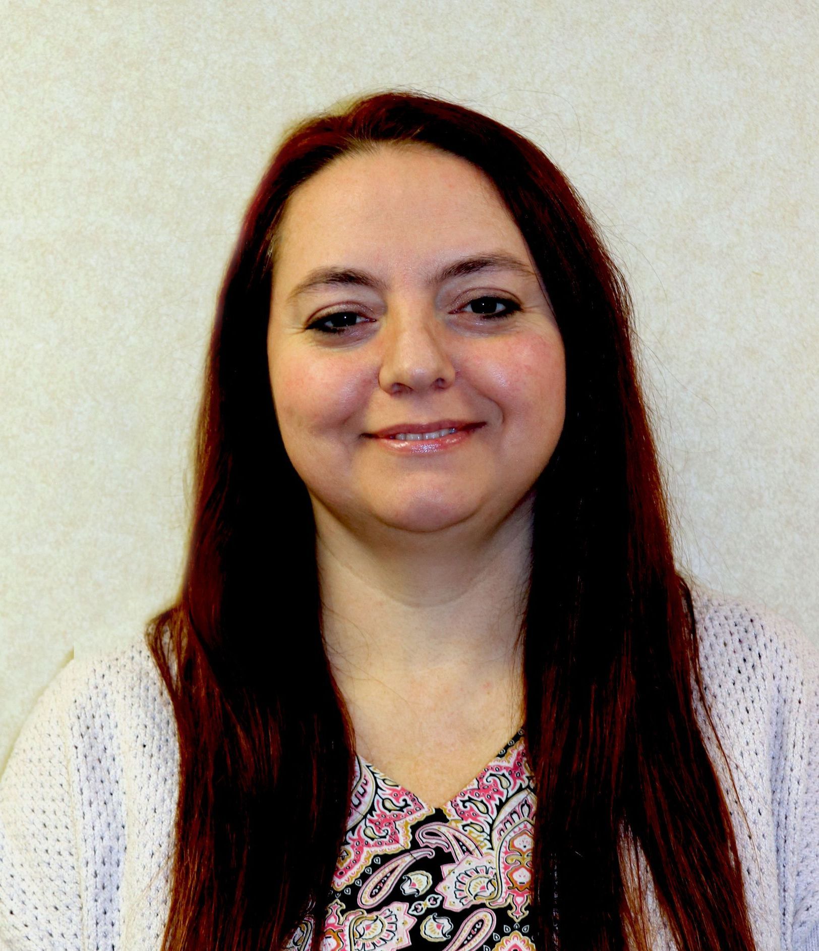 A woman with long red hair is smiling for the camera