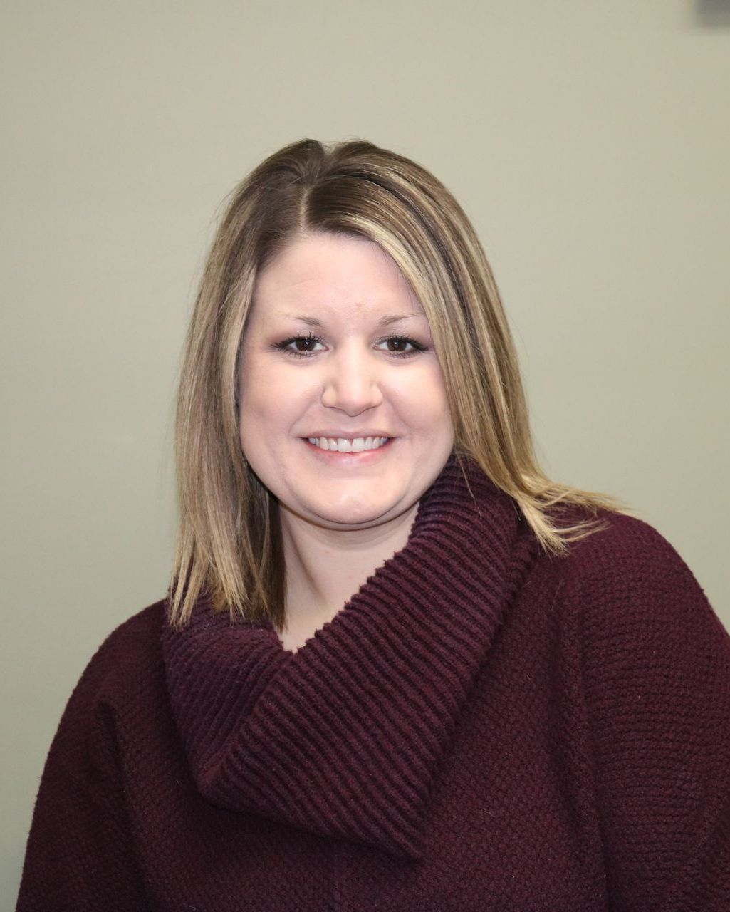 A woman wearing a purple sweater is smiling for the camera.