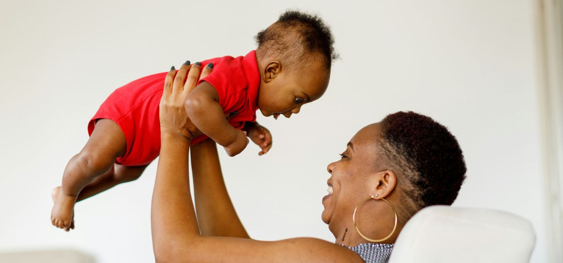 A woman is holding a baby in the air.