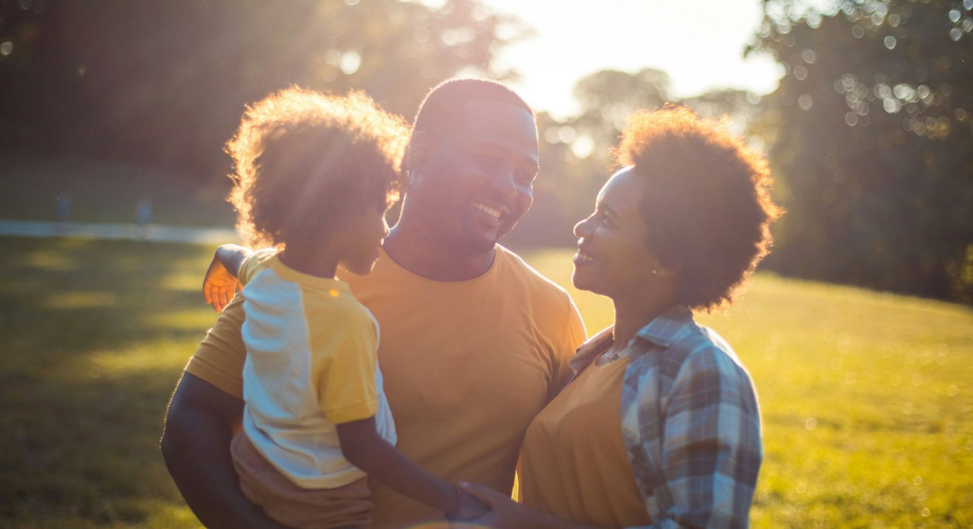 A man and woman are holding a child in a park.