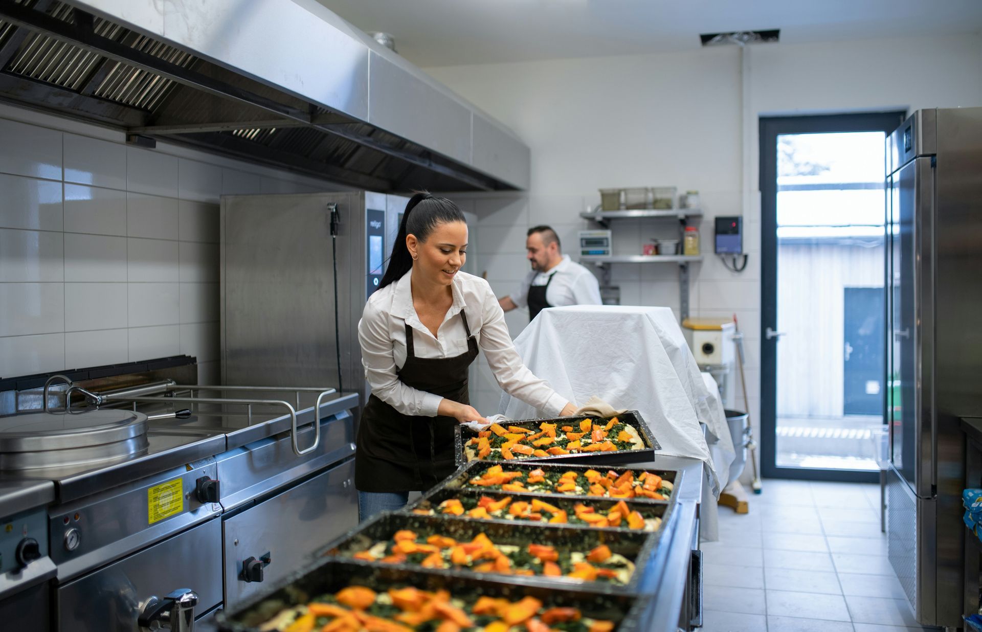 A woman is preparing food in a commercial kitchen.