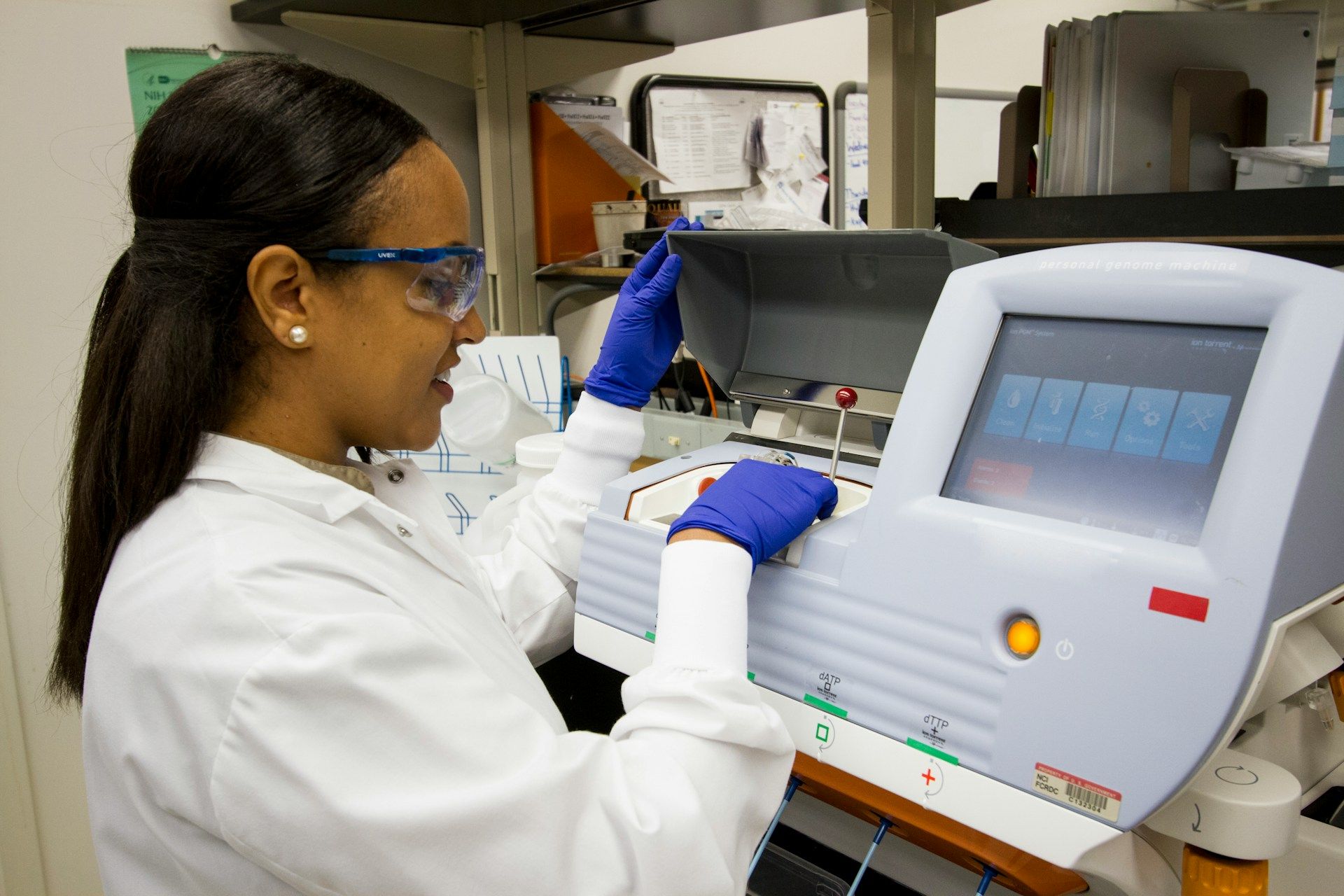 A woman in a lab coat is working on a machine.