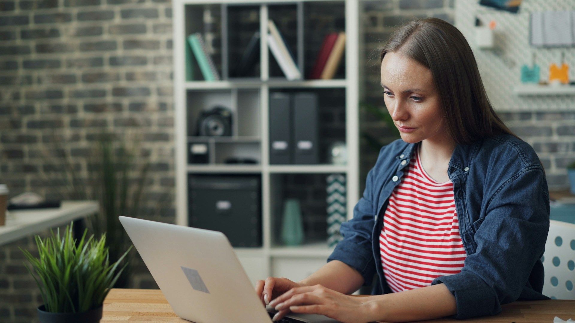 A woman is sitting at a table using a laptop computer.