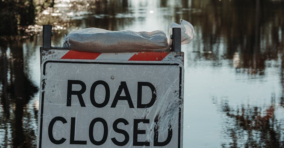 A road closed sign is sitting in the middle of a flooded area.