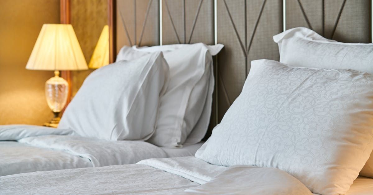 A bed with white sheets and pillows in a hotel room.