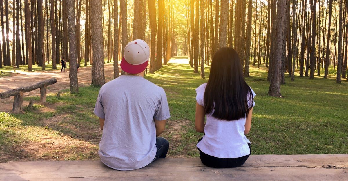 A man and a woman are sitting on a bench in the woods.