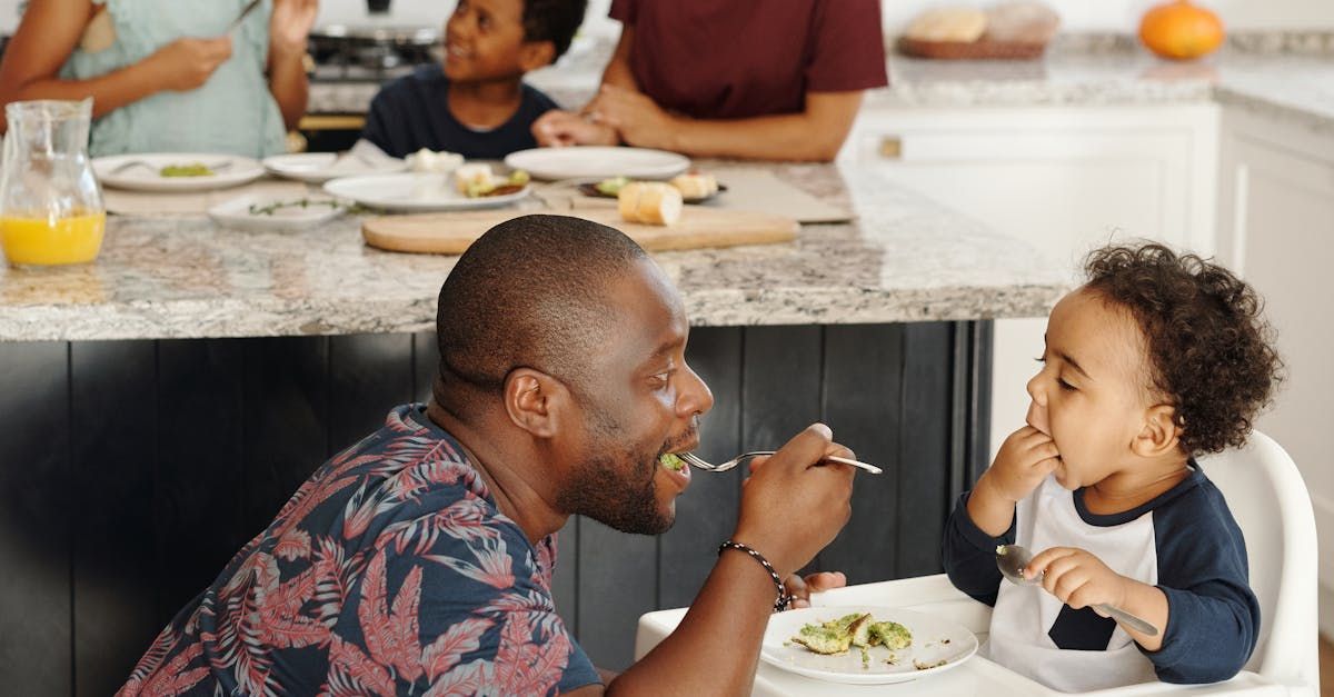 A man is feeding a baby in a high chair.