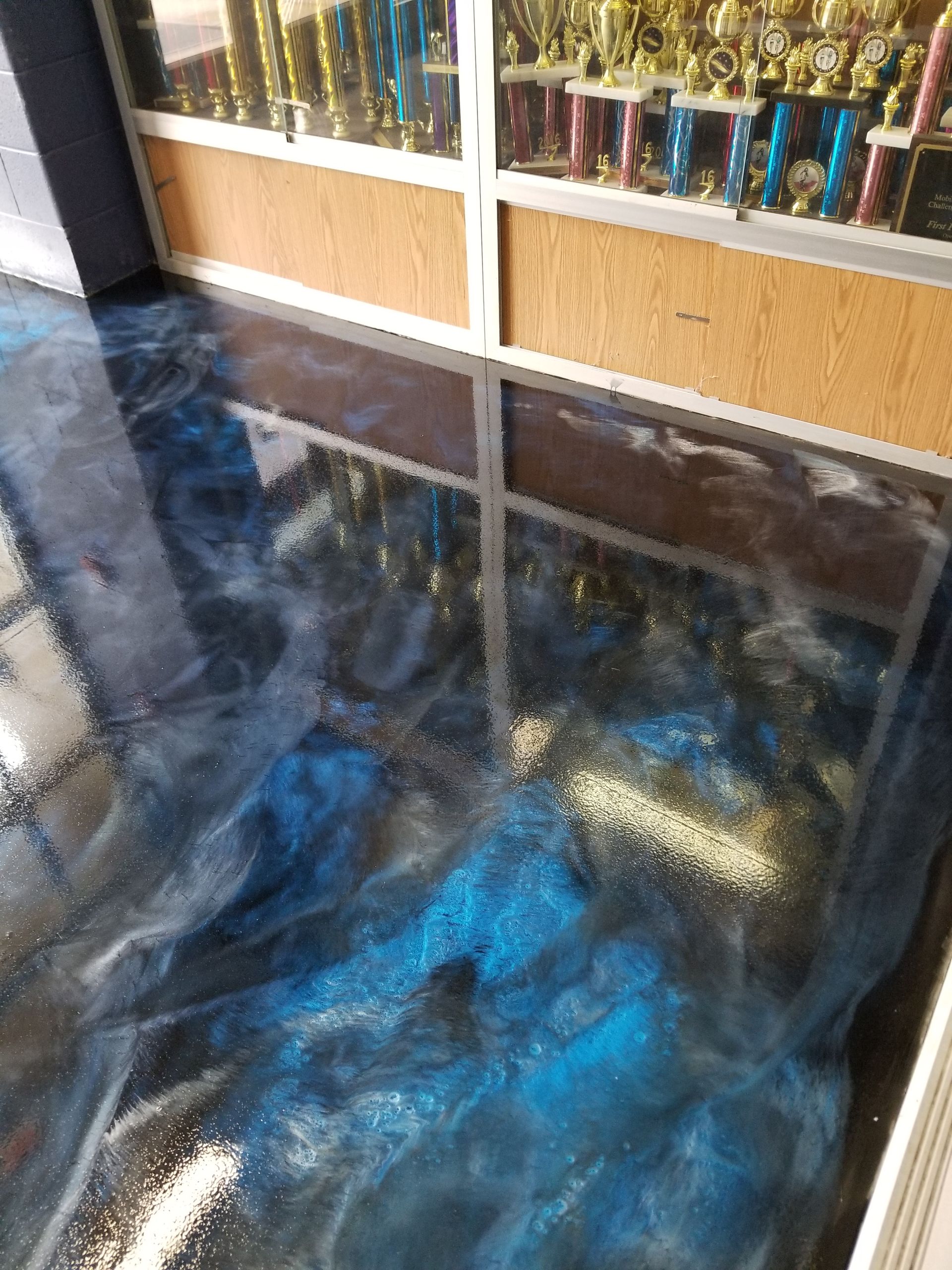 Metallic blue and silver epoxy floor reflecting trophy display.