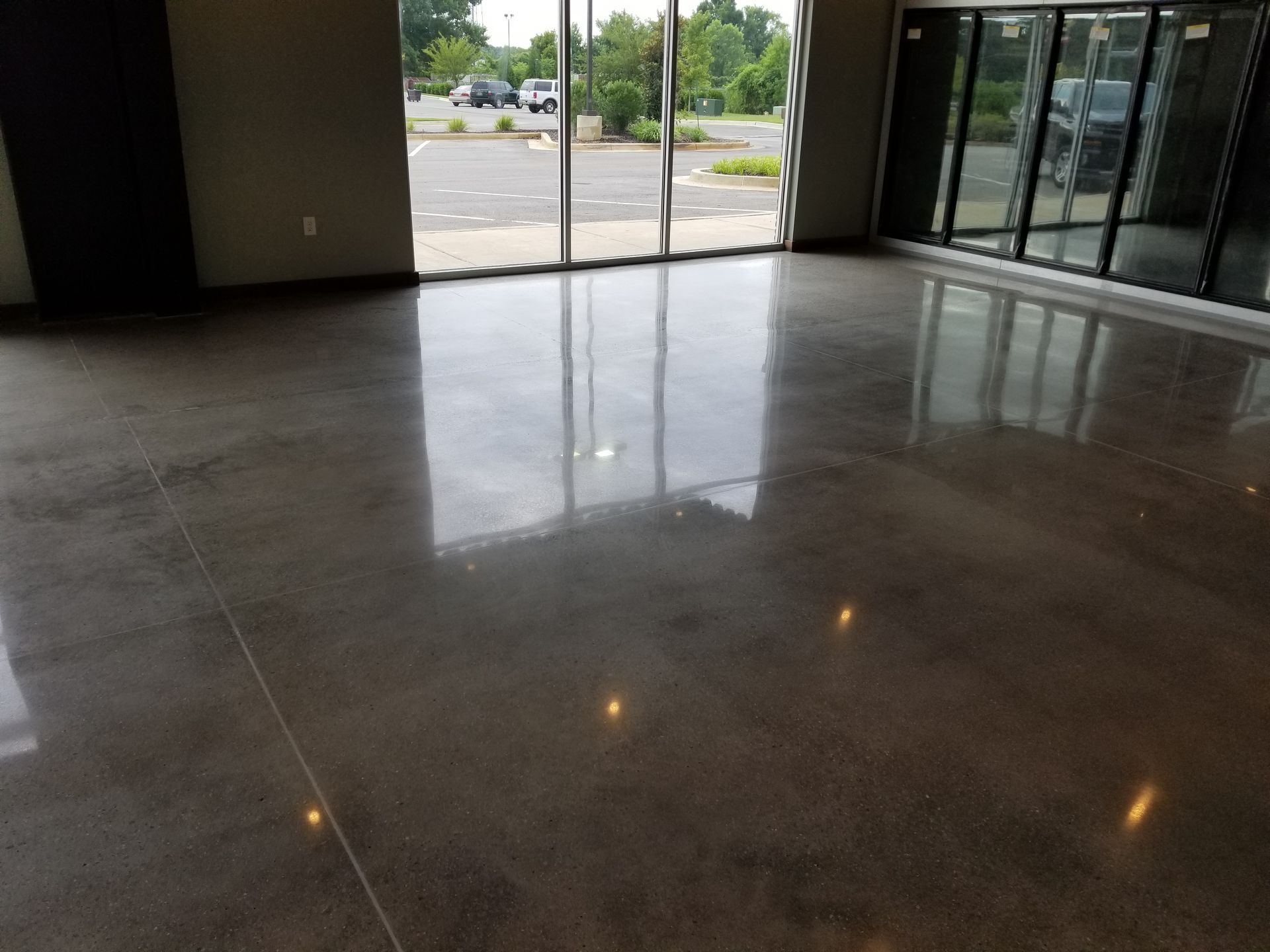 Polished concrete floor reflecting natural light from large windows. Interior of a commercial space.