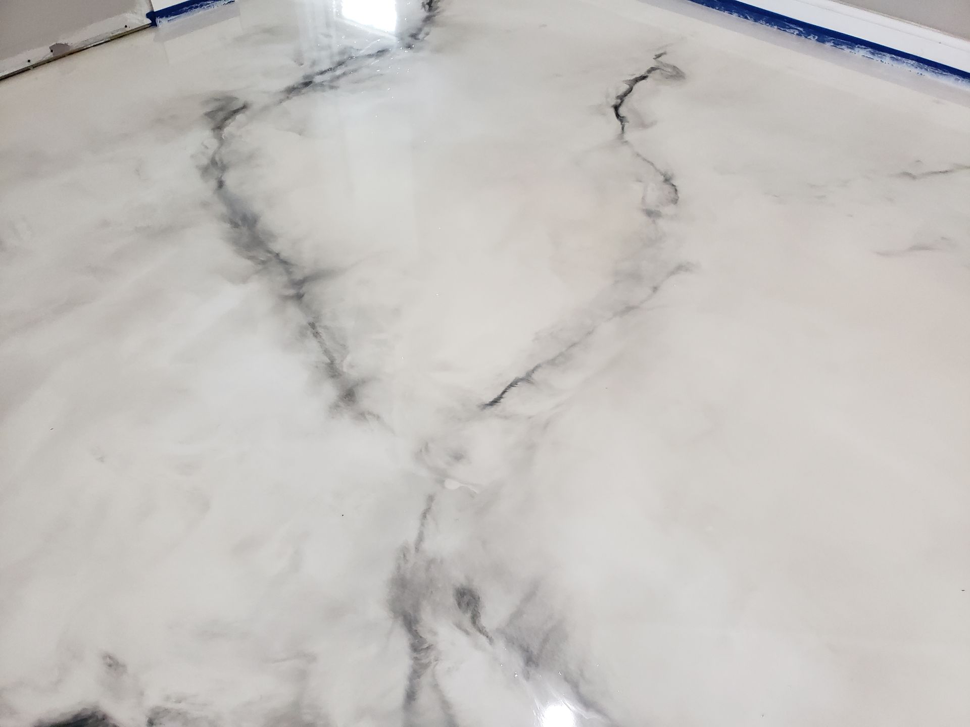 White epoxy floor with grey veining, creating a marble-like appearance.