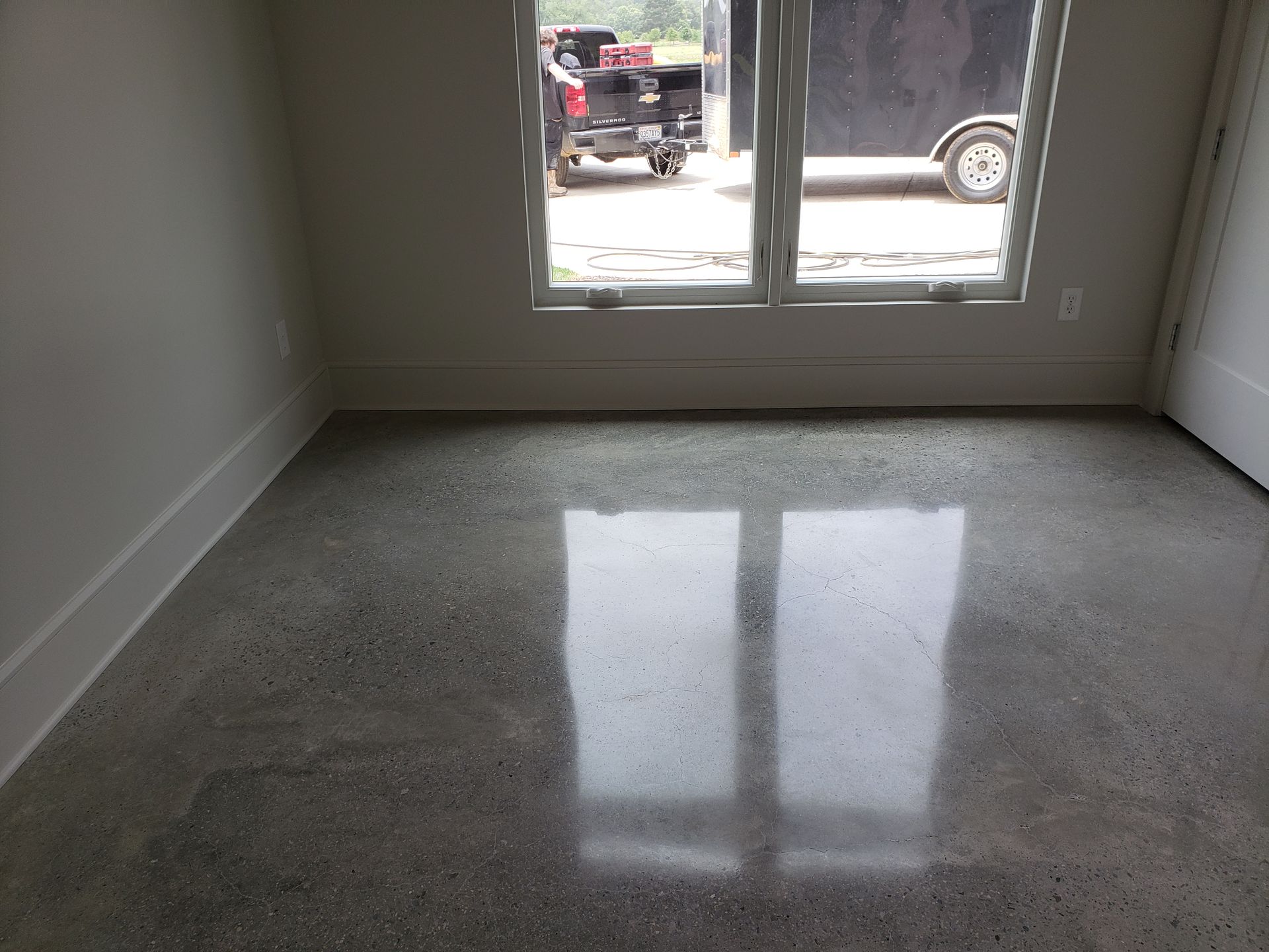 A room with a polished concrete floor. Sunlight reflects from the window onto the floor.