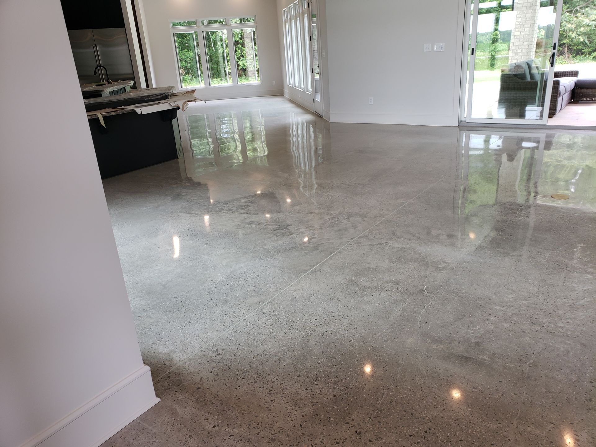 A living room with a shiny polished concrete floor and a sliding glass door.