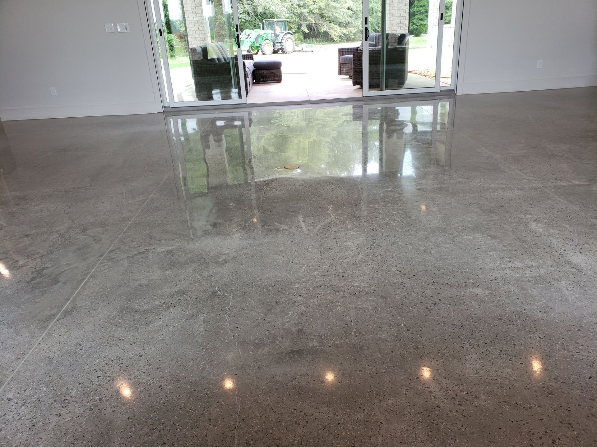 Polished concrete floor reflecting the outdoors through glass doors; a light gray interior.