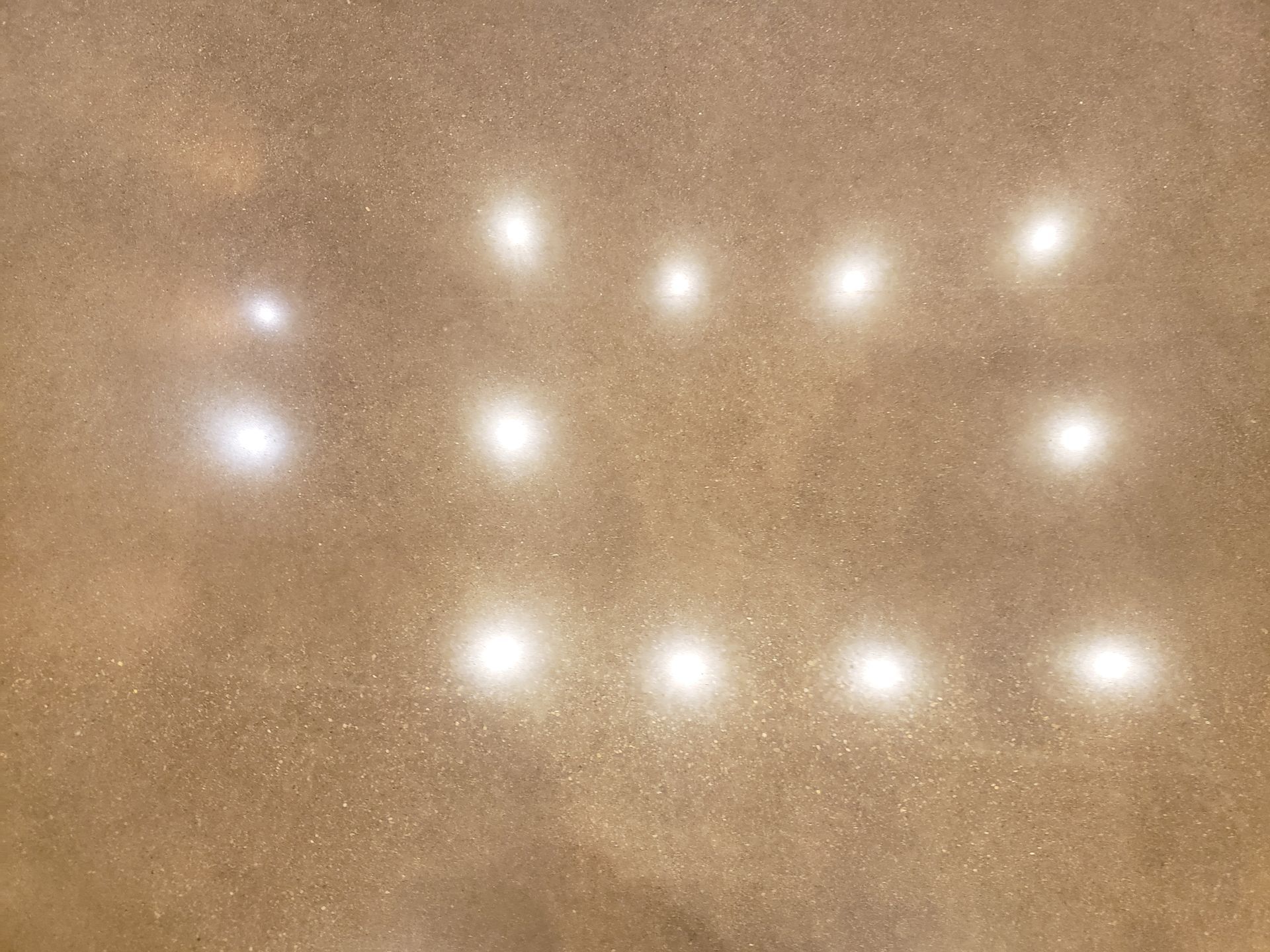 Tan floor reflecting bright overhead lights arranged in a rectangular pattern.