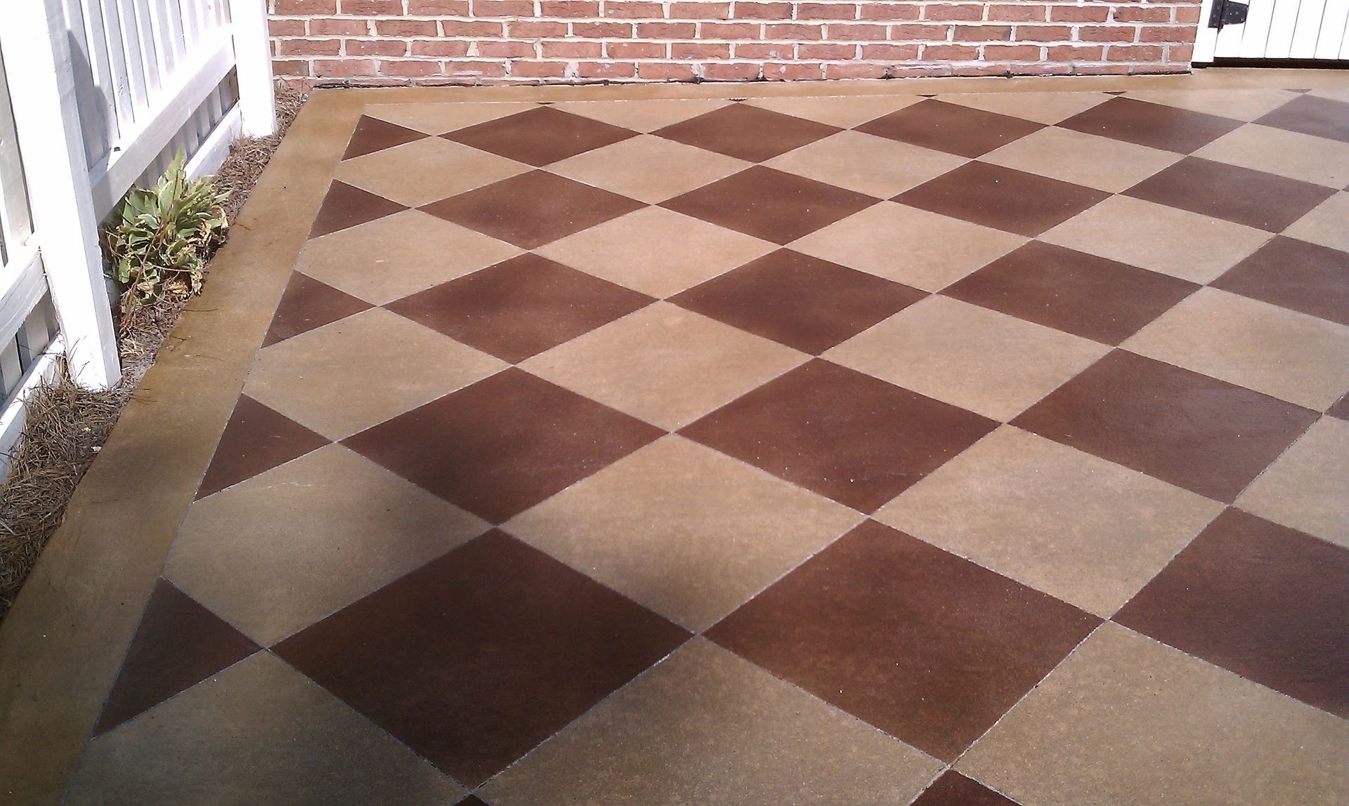 A brown and tan checkered floor with a white fence in the background