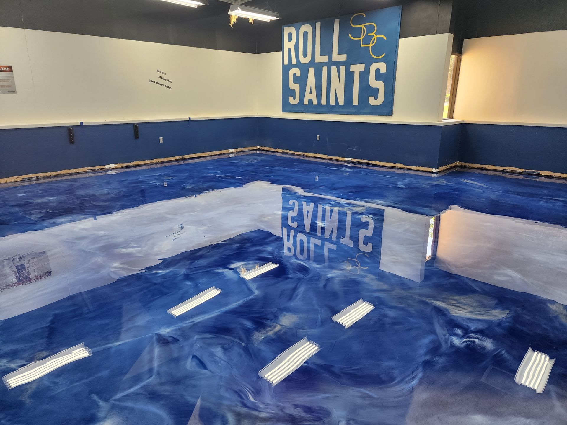 A gymnasium floor with a reflective blue epoxy finish.