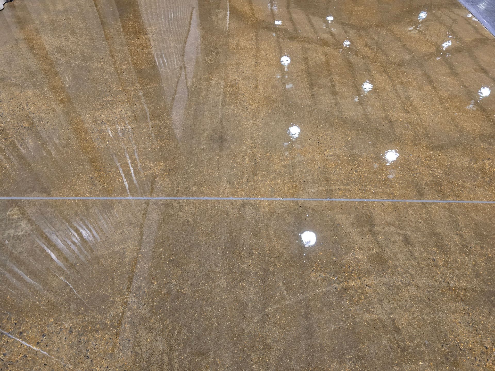 Shiny, brown concrete floor with a visible seam; reflections of lights are visible.