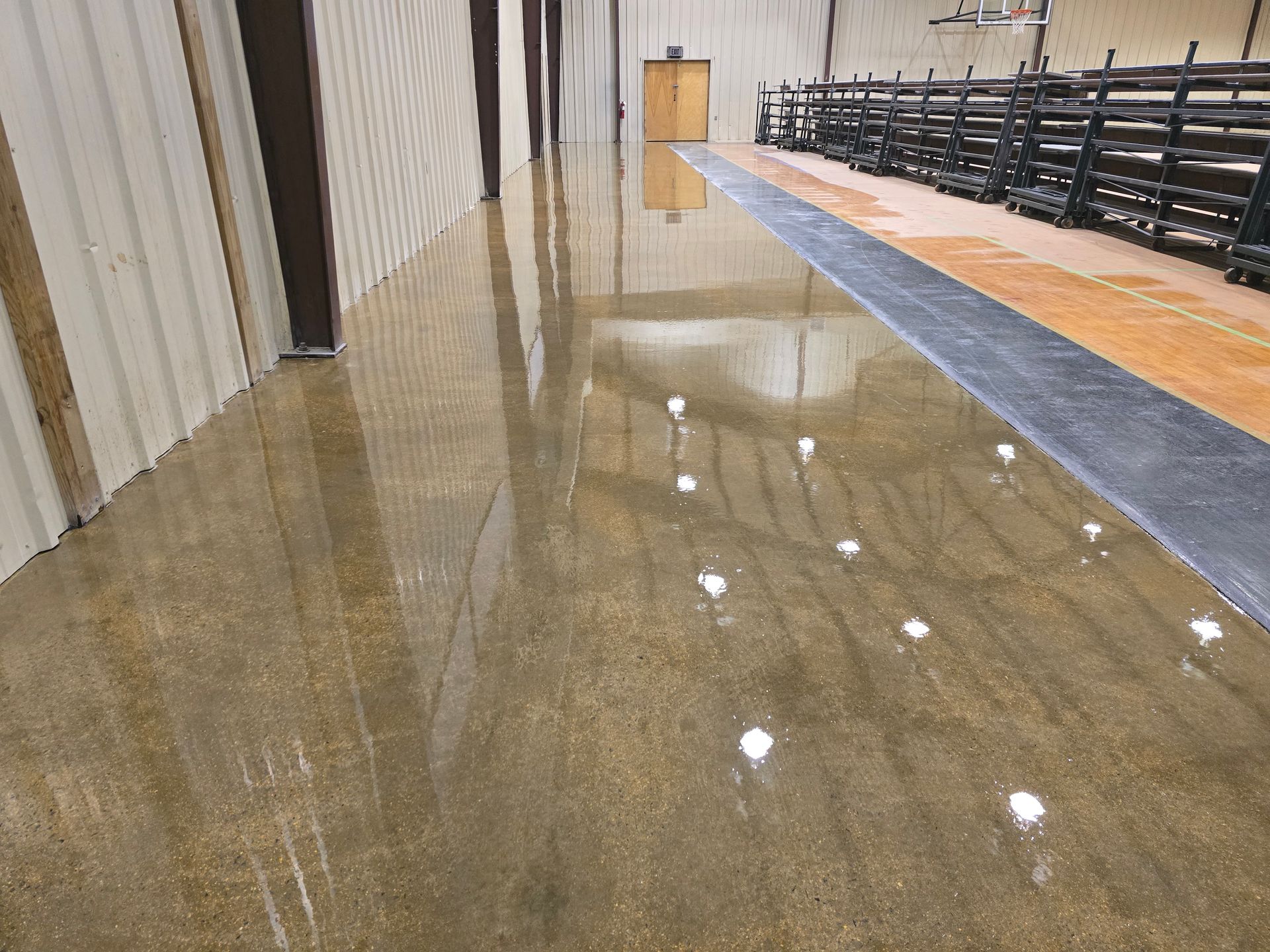 Polished concrete floor in an industrial setting. The floor reflects the ceiling lights and surrounding walls.