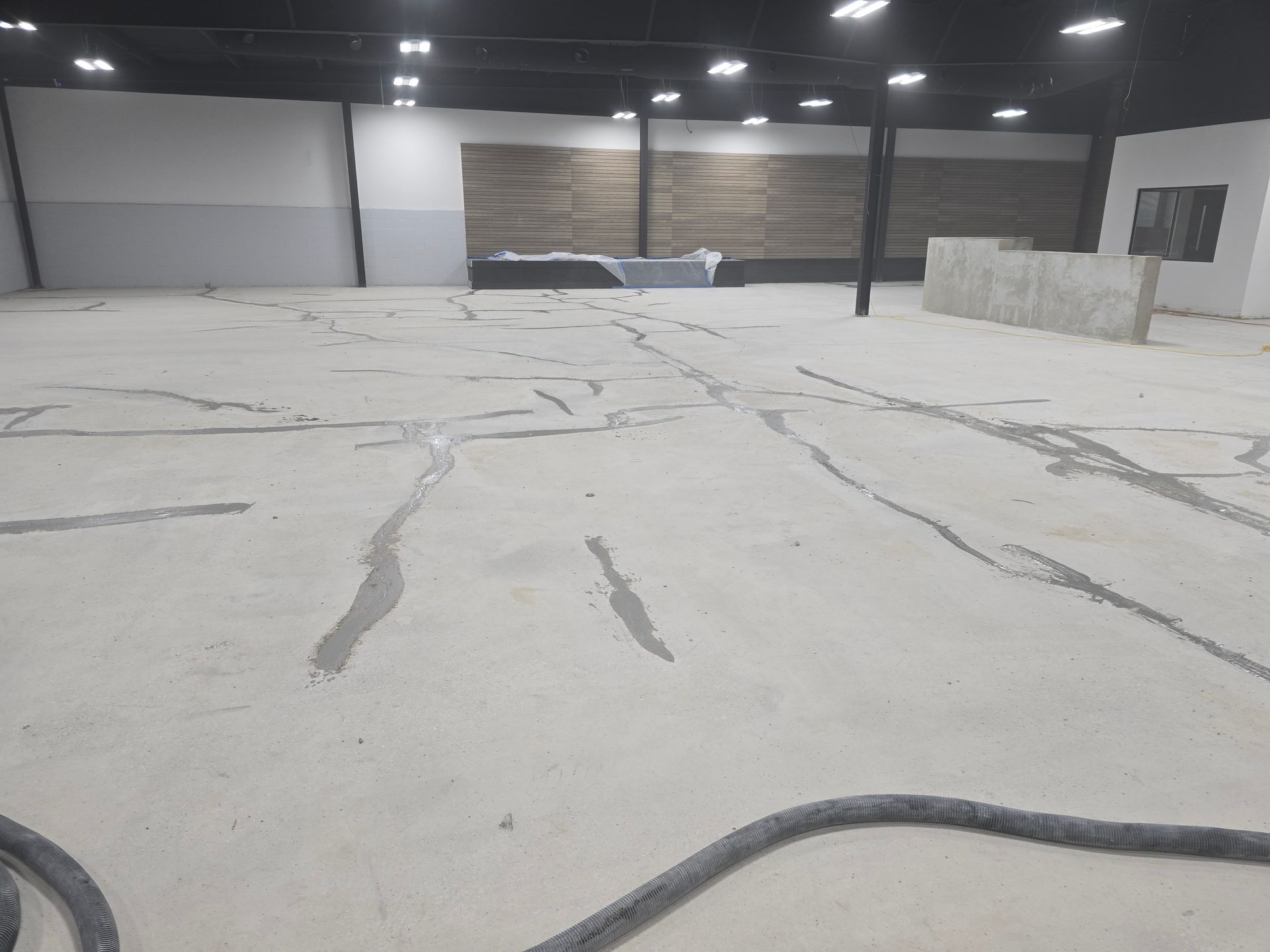 Empty warehouse interior with cracked concrete floor. Patches of new material fill cracks.