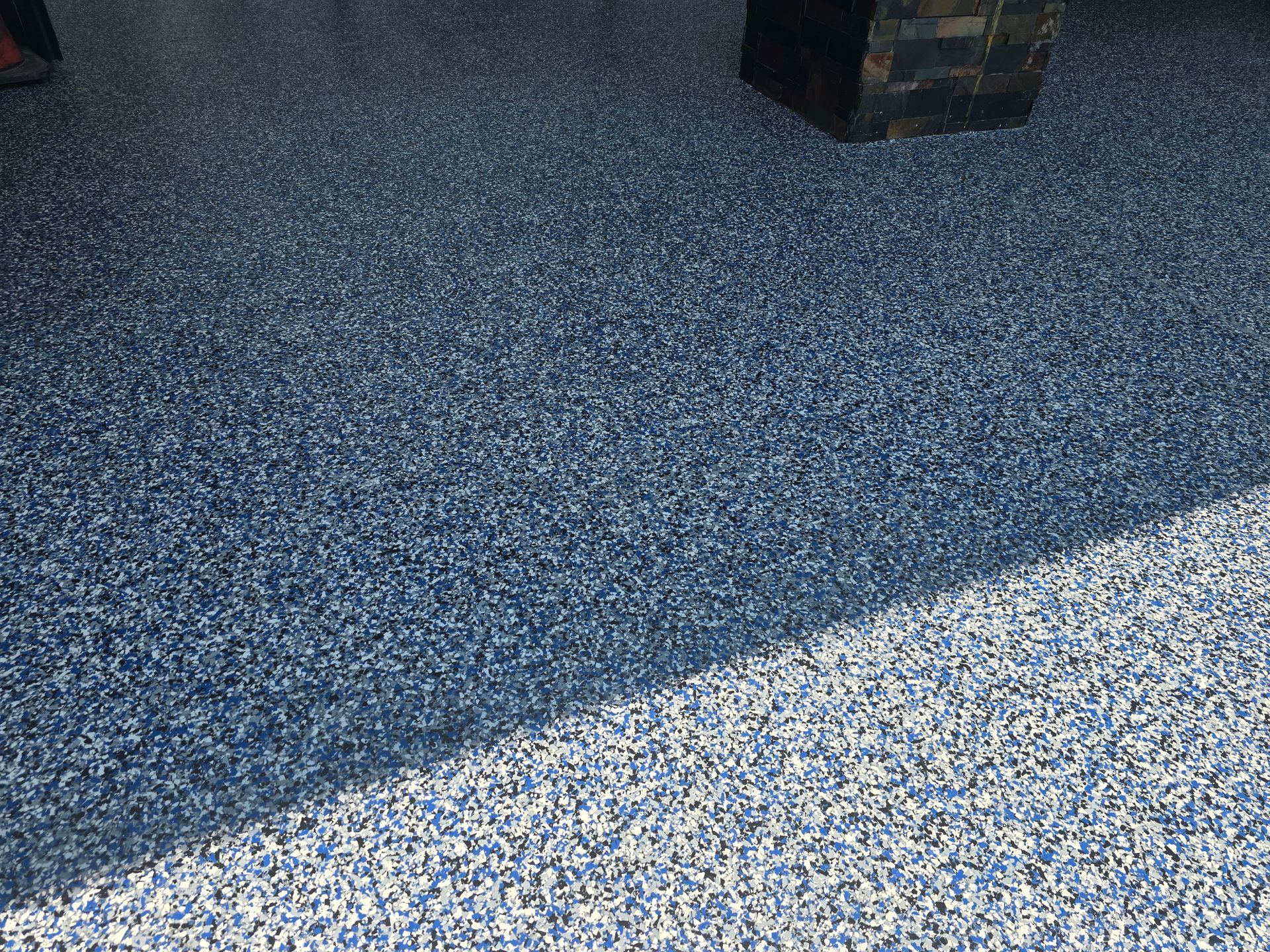 Blue and white speckled epoxy floor with a shadow from a nearby object.