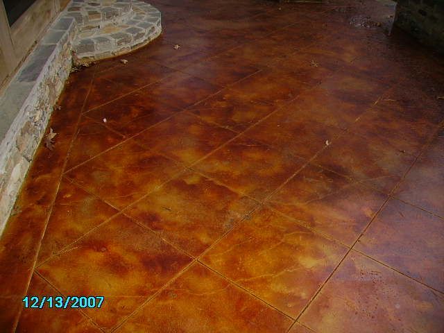 Brown and gold stained concrete patio with diamond grid pattern, near a stone wall, stained on 12/13/2007.