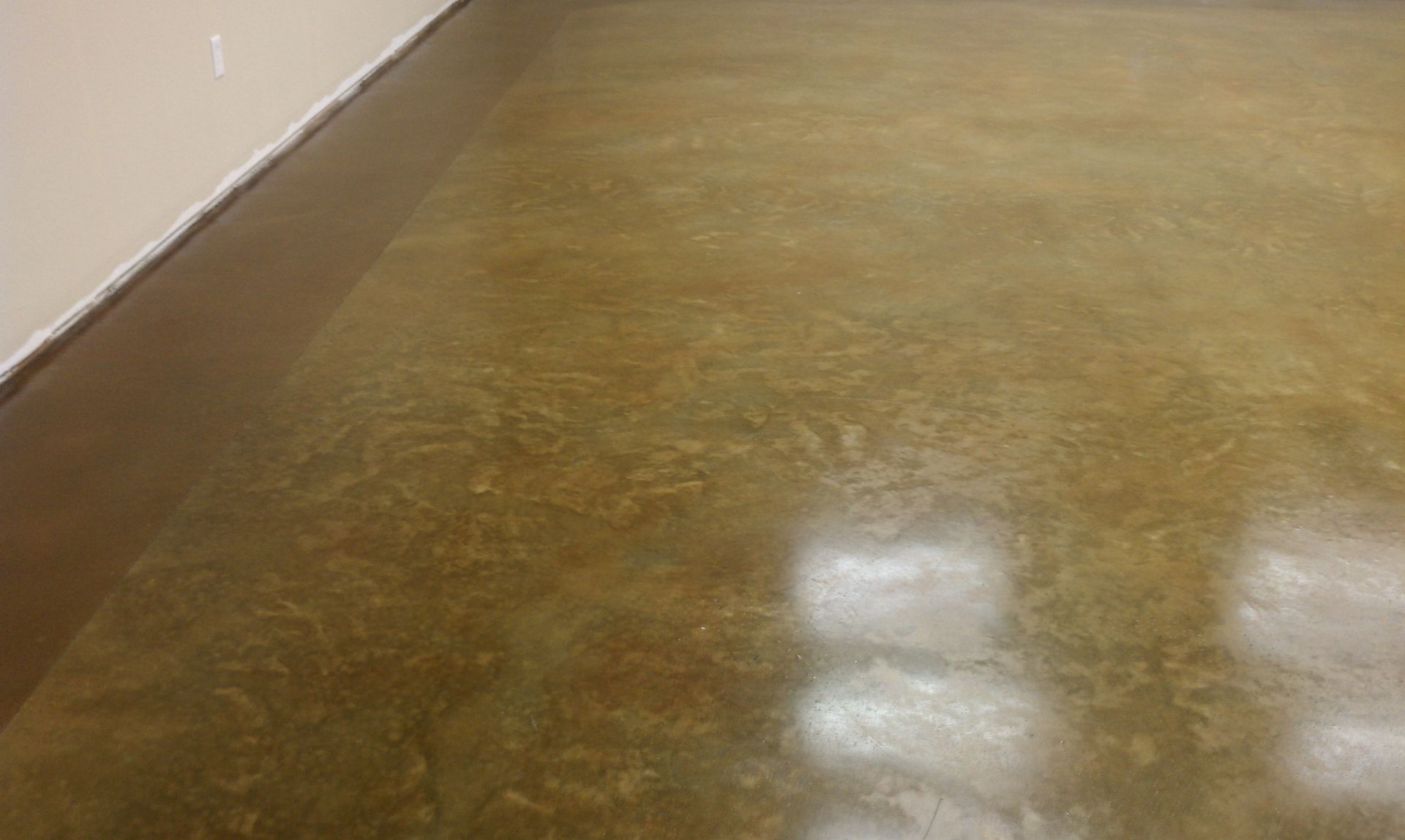 A close up of a shiny stained concrete floor in a room.