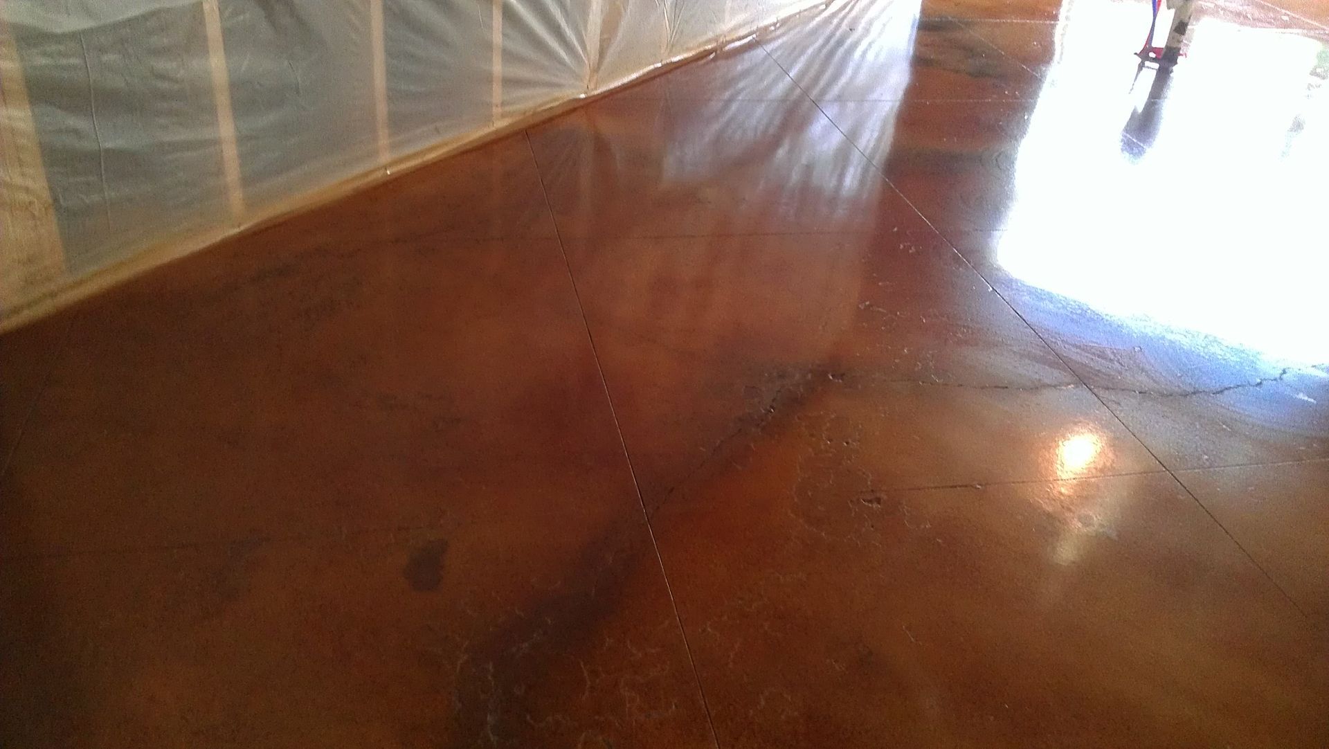 Brown stained concrete floor reflecting sunlight and shadows.