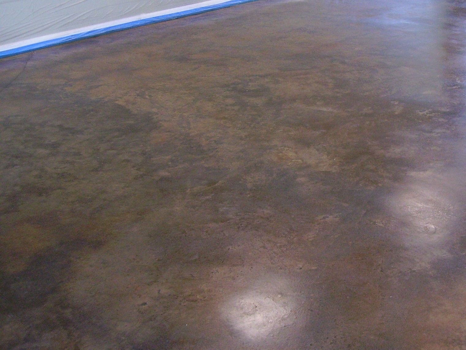 Brown stained concrete floor with variations in color and sheen.
