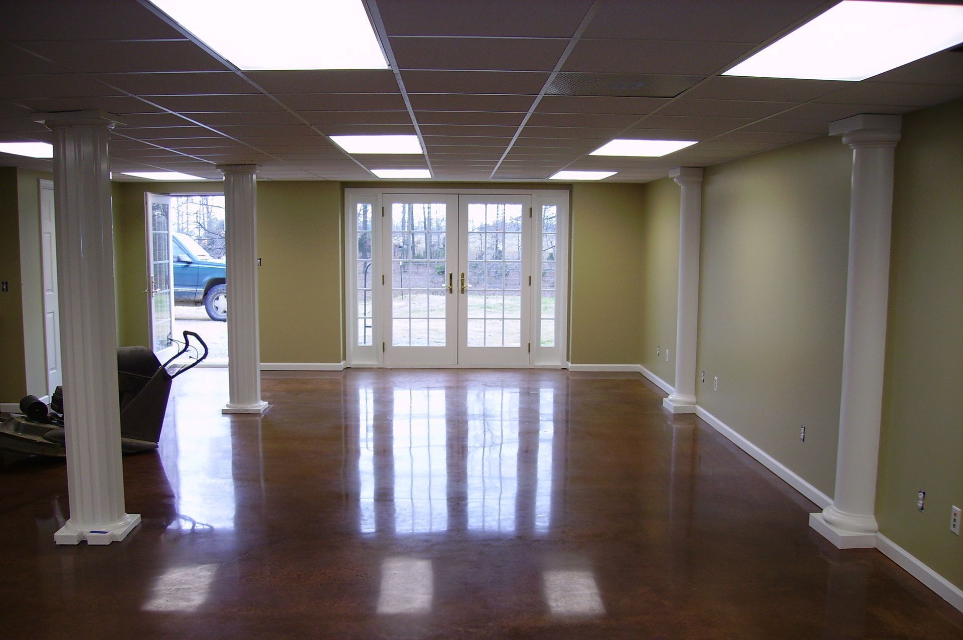 The polished concrete floor of an empty room with columns and sliding glass doors