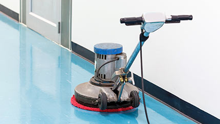A machine is cleaning a blue floor in a hallway.
