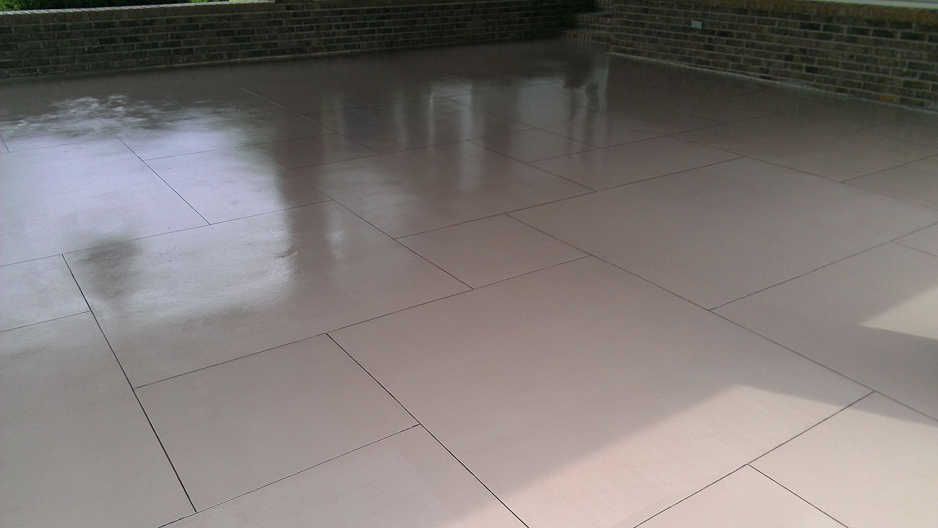 A stained, white, tiled floor with a brick wall in the background.