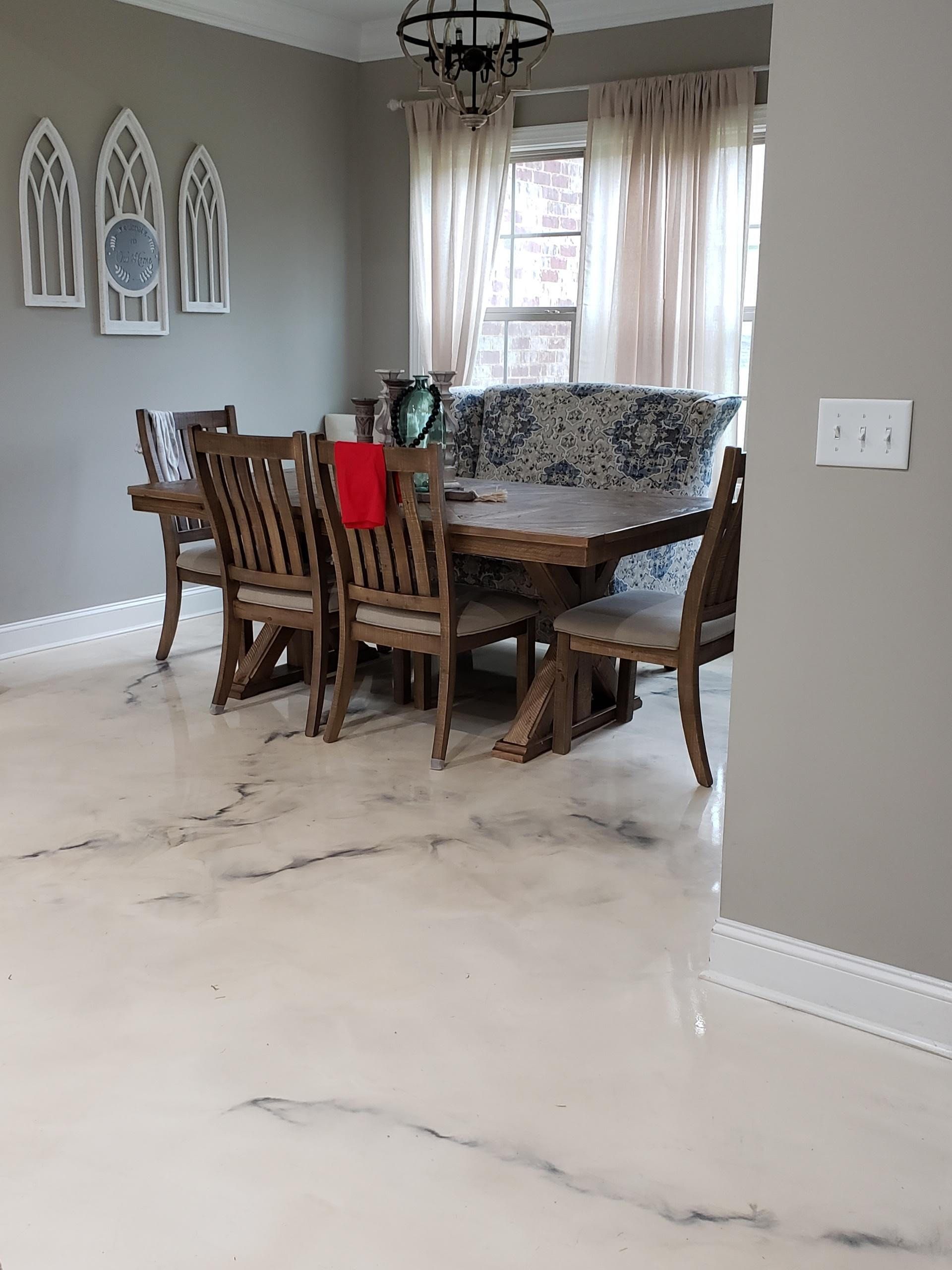 Dining room with a large wooden table, chairs, and light-colored flooring. A decorative wall piece hangs on a gray wall.