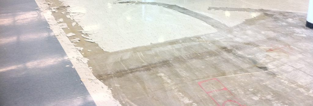 A machine is cleaning a blue floor in a hallway.