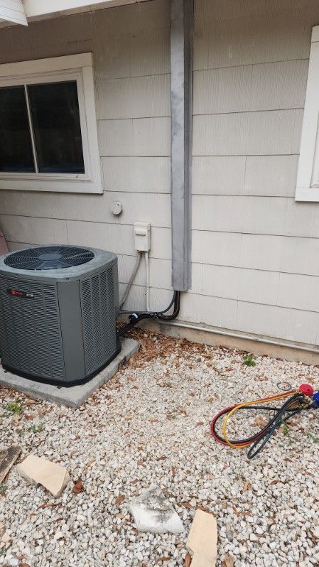 An air conditioner is sitting on the side of a house.
