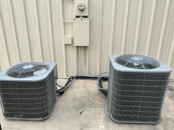 Two air conditioners are sitting next to each other outside of a building.
