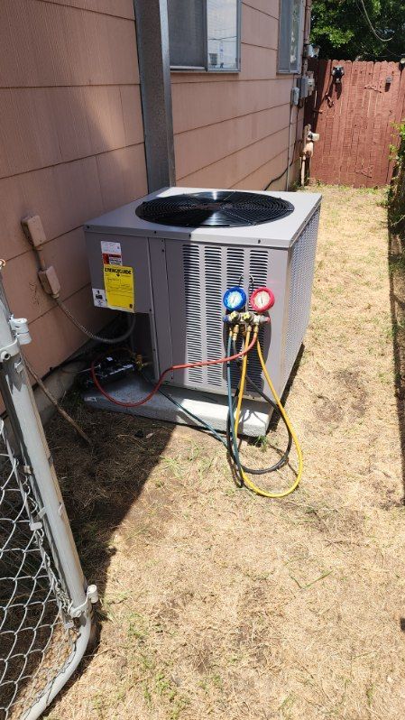 An air conditioner is being installed in the backyard of a house.